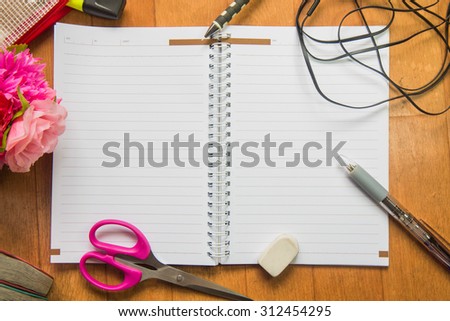 Blank space of notepad with supplies and flower. Top view with copy space