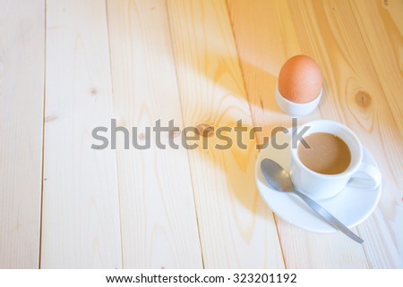 Coffee cup with boiled egg in the morning sunshine on wood floor