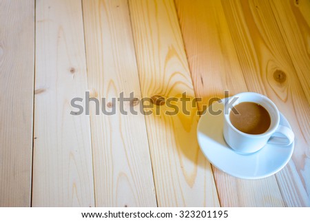 Coffee cup in the morning sunshine on wood floor.
