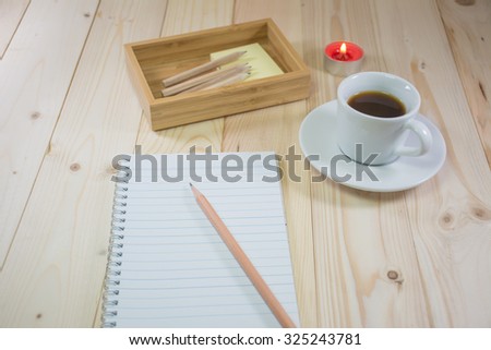 Blank Note and pencil with wooden table in dim light, coffee.
