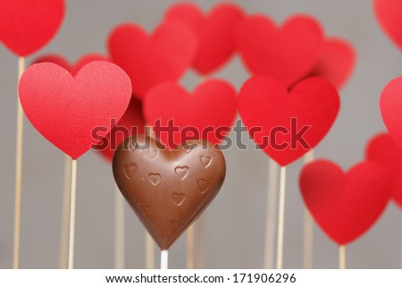 Valentine's day hearts on a stick with chocolate heart isolated on grey background