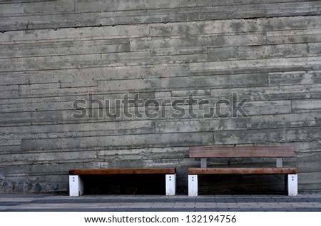 Modern benches contrasted against rustic concrete wall.