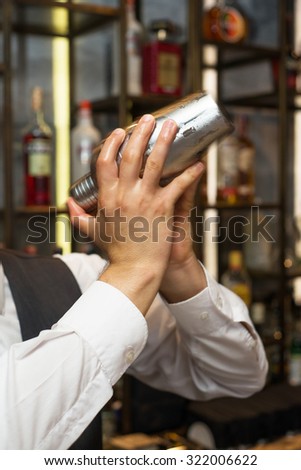 Barman at work, preparing cocktails. Shaking cocktail shaker. concept about service and beverages.