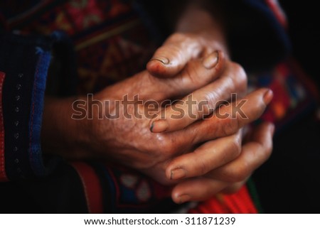 Old tribal woman with wrinkle hands clasped.