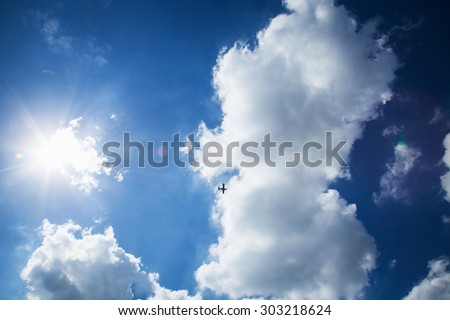 Sun shining on the sky with clouds and aircraft.