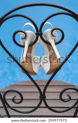 White wedding shoes placed on a chair near the pool