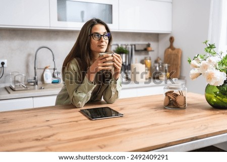 Image, Stock Photo Pensive woman drinking coffee and browsing smartphone at table