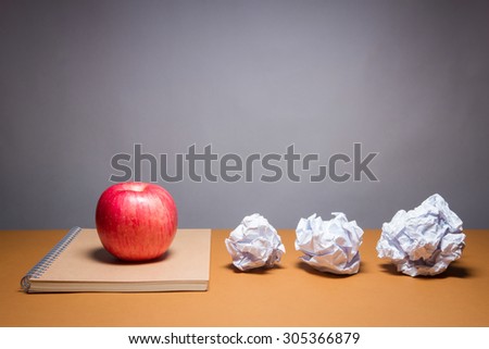 an apple on a notebook and crumpled paper. Business frustrations, Job stress and Failed exam concept.