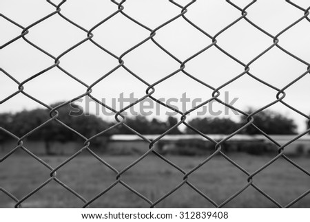 chain link fence with grass field. Black and White filter