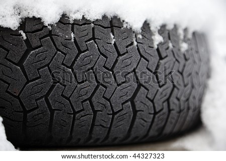 Car tyre frosted and covered with snow. Shallow depth of field.