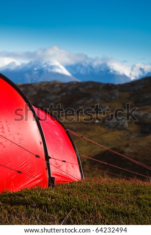 A red tent pitched in mountainous terrain in northern Norway. Strong color contrast between the tent and its surroundings.