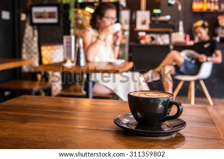 Coffee cup in coffee shop with blur people (selective focus at cup)