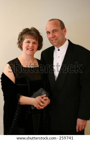 A middle aged couple formally dressed.  Soft lighting.