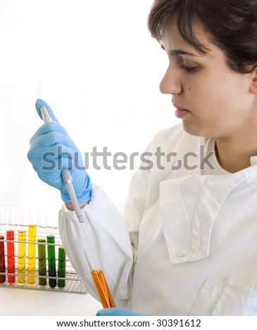 Lab Tech pipetting orange sample. Colorful test tubes on background.