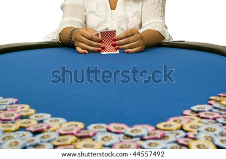 A woman holds her cards on a blue felt table with poker chips spread out in the foreground.