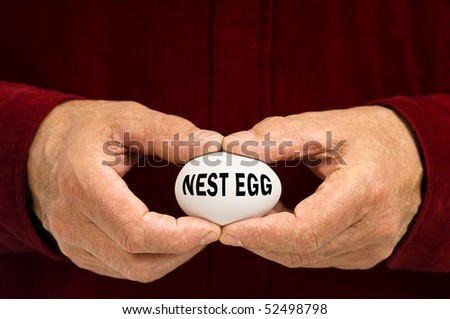 A man holds a white egg with NEST EGG written on it, symbolizing the fragility of money matters and the proverbial \'nest egg.\'