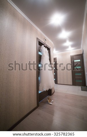 The wedding dress on a hanger in the room of the bride