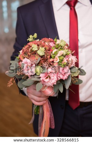 groom hold wedding bouquet in his hand