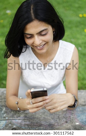 South Asian woman on cellular phone in the park