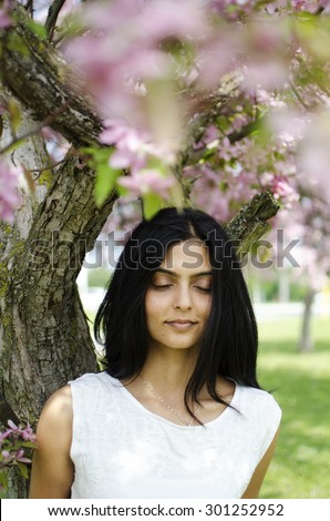 Young, South Asian woman standing in a park under an apple blossom tree