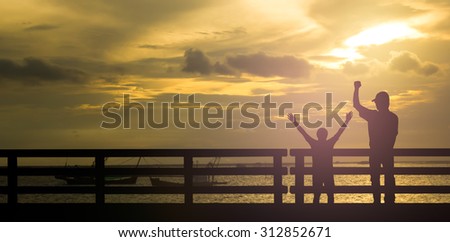 Silhouette successful man or winner man on over blur Beautiful evening sunset above the sea and boat background
