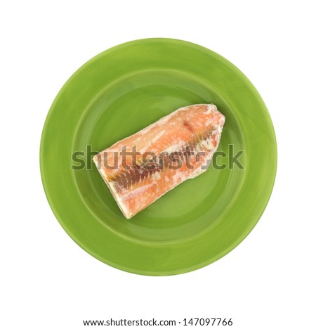 A slice of frozen salmon steak on a green plate.