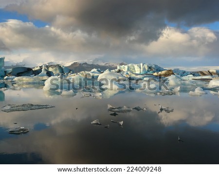 Reflection of rainclouds and floating icebergs in Jokulsarlon glacier lake in Iceland. This is a lake where icebergs calve from Vatnajokull glacier and float around until they melt.