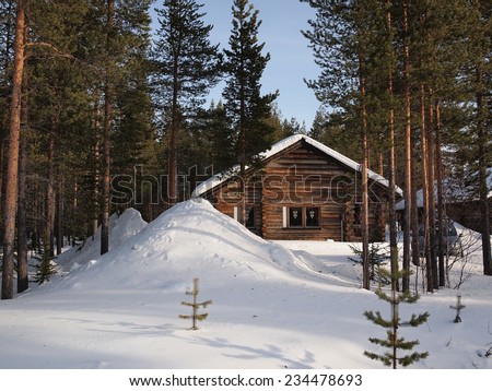 Romantic snow covered chalet in a forest of pine trees in a holiday resort in Lapland, Finland. Perfect for the christmas holidays.