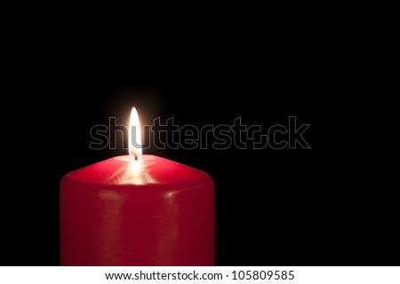 Red candle isolated against a black background