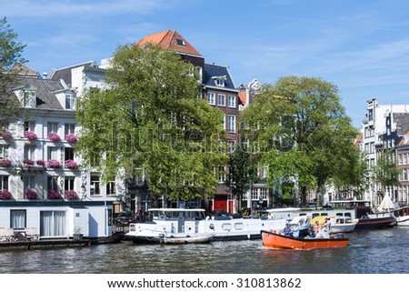 AMSTERDAM, THE NETHERLANDS - AUG 06: Small boat with relaxing people in Amsterdam canal on August 06, 2015 in Amsterdam, the Netherlands