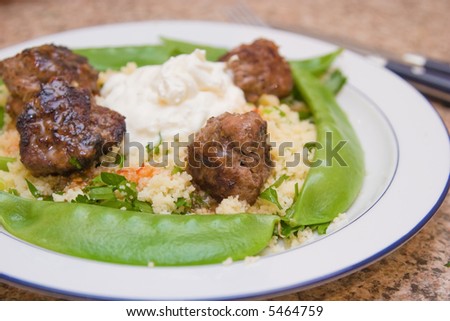 Meal consisting of meatballs, couscous, yogurt and snow peas