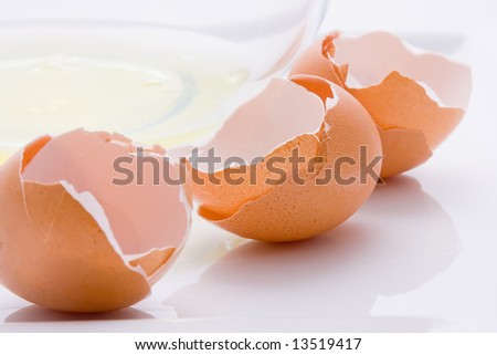 Three broken eggs and a bowl with egg white