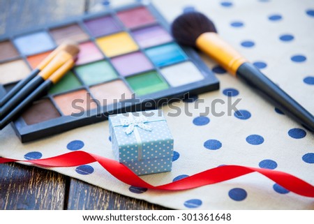 Gift box and brushes for makeup with palette on polka dot background