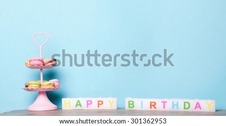 Colorful macarons on blue background with happy birthday candles