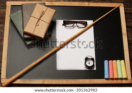 Blackboard with books and subjects on the woodeb background
