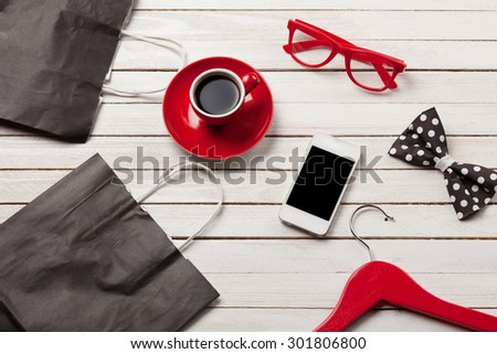 Cup of coffee with lipstick  shopping bags and mobile phone on the wooden background