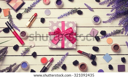 Gift box and cosmetics on white wooden table.