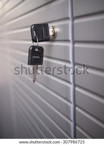 Detail of a black key in the lock of a grey office cupboard.