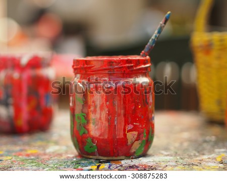 Old jar covered with red paint and brush - tools for painter