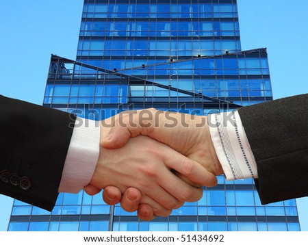 Businessmen shaking hands in front of the Skyscraper on the blue Sky