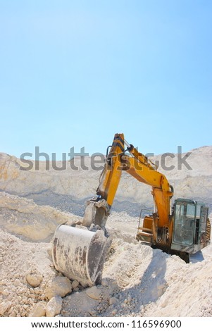 Caterpillar excavator in chalk pit against a blue sky