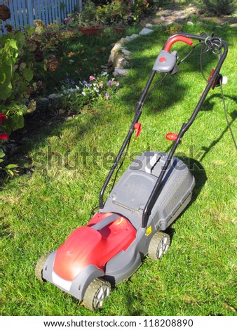 Modern electric lawn mower on the mown down lawn