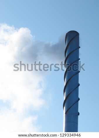 Steel smoking stack of the modern boiler-house against a blue sky