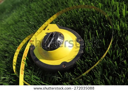 Measuring tape lying on the fresh mow lawn grass in the summer garden