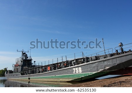 Transport military barge at the river bank against a blue sky