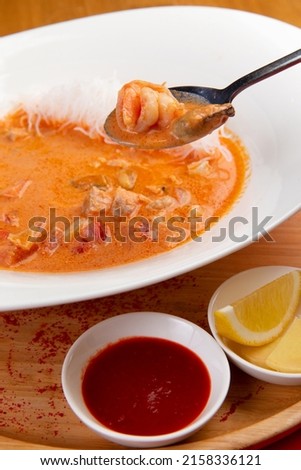 In a spoon Traditional tom yum soup. On a red background. Selective focus. Imagine de stoc © 