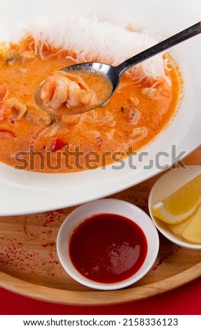 In a spoon Traditional tom yum soup. On a red background. Selective focus. Imagine de stoc © 