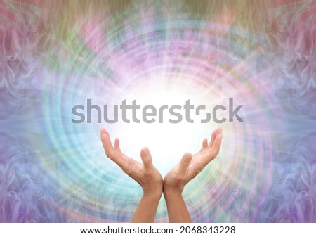 Channeling healing energy vortex spiral - female cupped hands reaching up into a white vortex energy against a multicoloured  spiralling light background with copy space
 ストックフォト © 