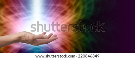 Female Healer with hand out palm up and a shaft of white energy on rainbow colored energy formation background banner