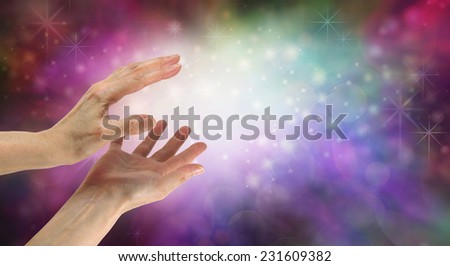 Beautiful Healing Energy Field  -  Female hands reaching out to sparkling white light on a pink and purple colored bokeh  background